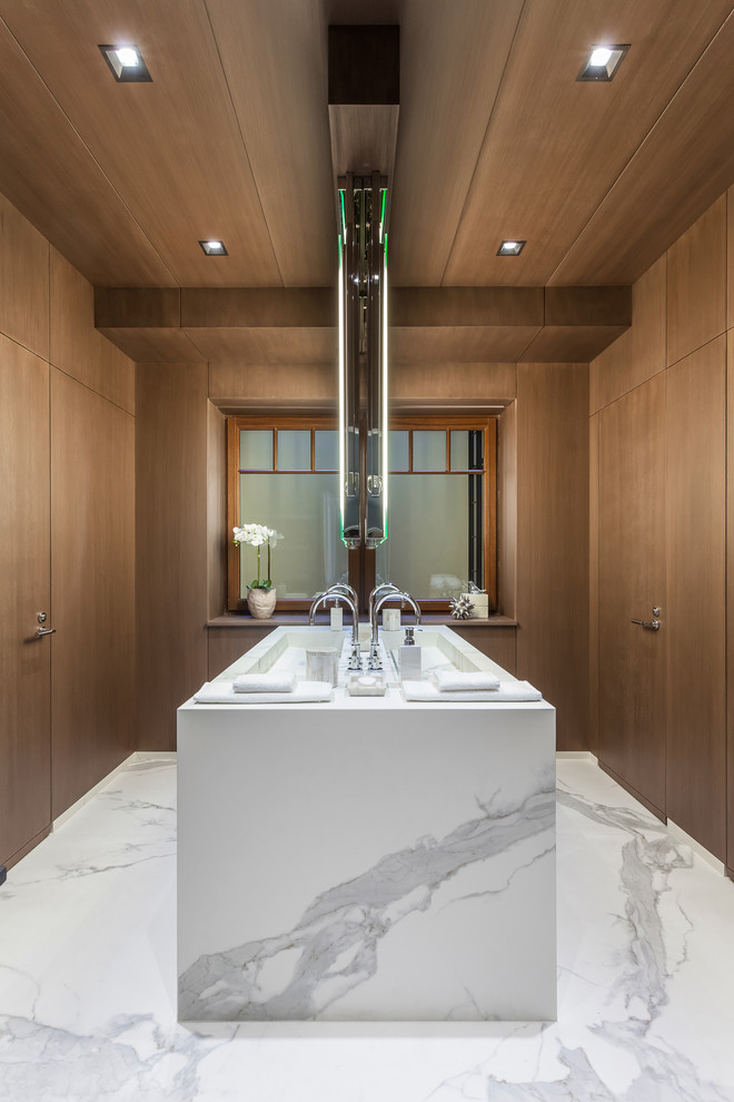 This is an example of a contemporary master bathroom in Miami with dark wood cabinets, marble benchtops, marble floors, a trough sink and flat-panel cabinets.
