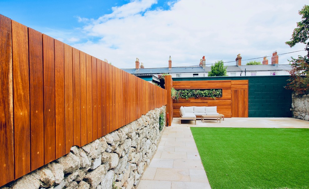 This is an example of a mid-sized contemporary backyard full sun formal garden for summer in Dublin with a vertical garden, natural stone pavers and a wood fence.