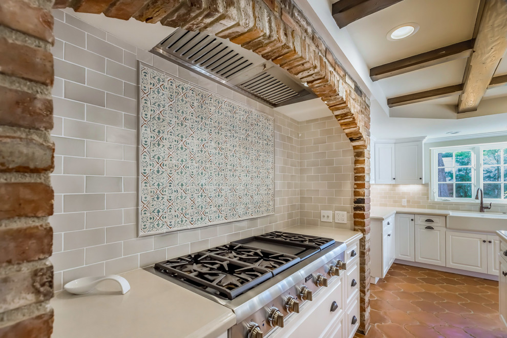 Inspiration for a large mediterranean galley kitchen pantry in Los Angeles with a farmhouse sink, raised-panel cabinets, white cabinets, quartz benchtops, multi-coloured splashback, porcelain splashback, stainless steel appliances, terra-cotta floors, with island and orange floor.