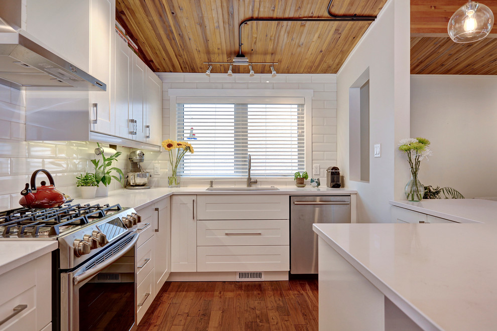 Eat-in kitchen - transitional u-shaped medium tone wood floor eat-in kitchen idea in Calgary with an undermount sink, shaker cabinets, white cabinets, quartzite countertops, white backsplash, subway tile backsplash, stainless steel appliances and an island