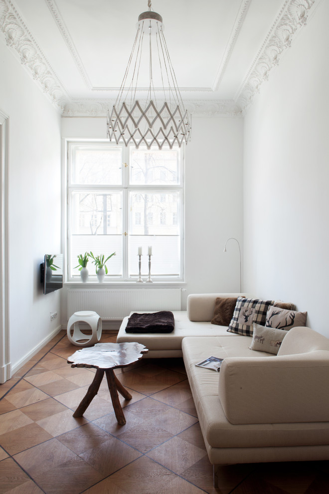 Inspiration for a small eclectic enclosed family room in Berlin with white walls, medium hardwood floors, no fireplace and a wall-mounted tv.