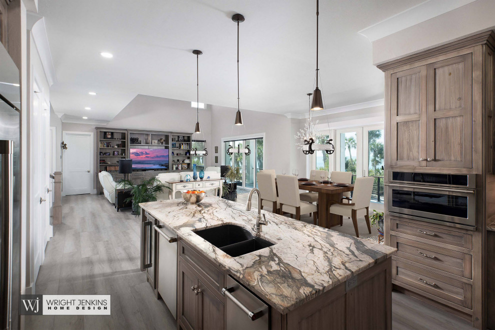 Photo of a mid-sized beach style u-shaped eat-in kitchen in Other with an undermount sink, recessed-panel cabinets, medium wood cabinets, granite benchtops, white splashback, ceramic splashback, stainless steel appliances, light hardwood floors, with island, grey floor and brown benchtop.