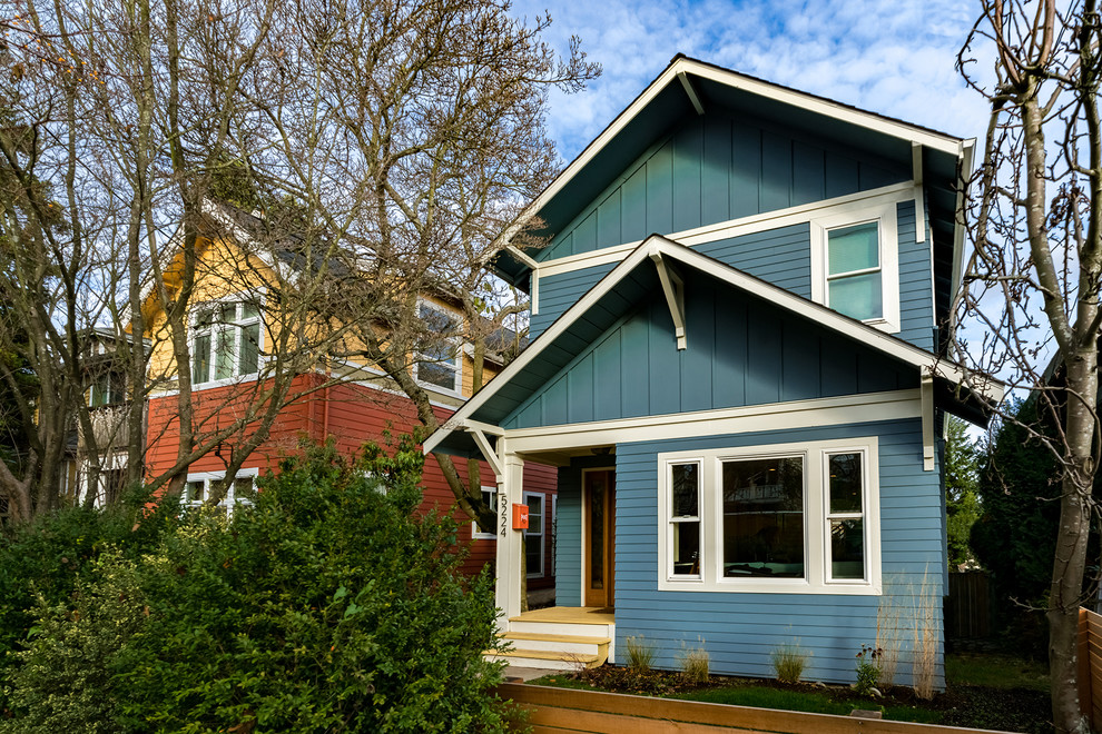 This is an example of a mid-sized arts and crafts two-storey blue house exterior in Seattle with concrete fiberboard siding, a gable roof and a shingle roof.