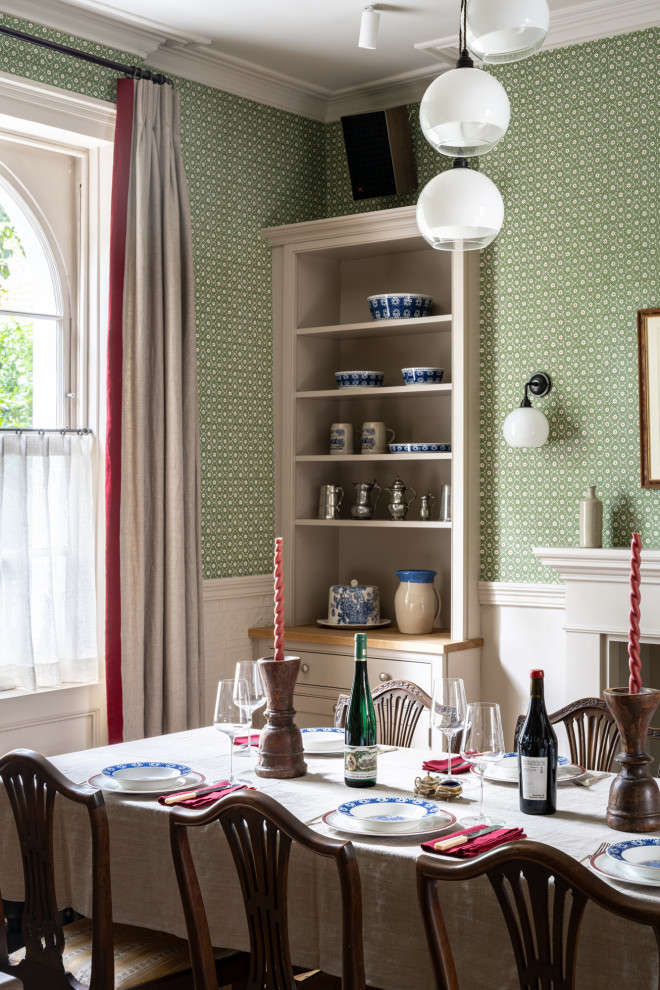 Photo of a classic dining room in London with green walls, medium hardwood flooring and wallpapered walls.