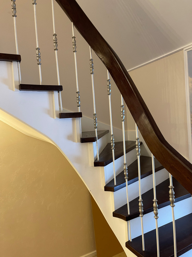 Идея дизайна: изогнутая деревянная лестница среднего размера в викторианском стиле с деревянными ступенями, металлическими перилами и обоями на стенах
