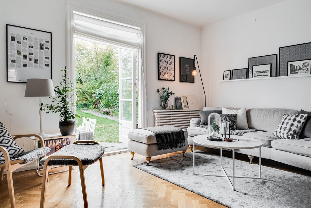 Design ideas for a mid-sized scandinavian living room in Gothenburg with white walls, medium hardwood floors and no fireplace.
