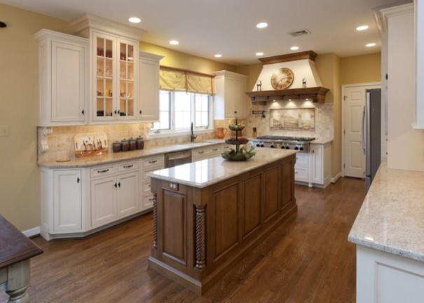 Photo of a large traditional u-shaped separate kitchen in Philadelphia with an undermount sink, recessed-panel cabinets, white cabinets, granite benchtops, beige splashback, travertine splashback, stainless steel appliances, medium hardwood floors, with island, brown floor and beige benchtop.
