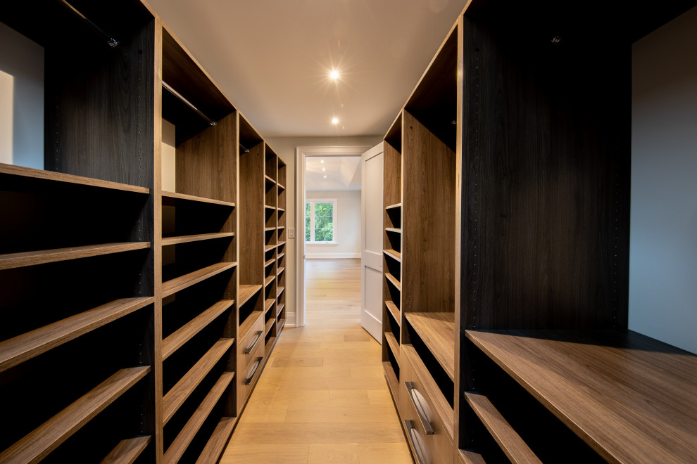 Photo of a large contemporary gender-neutral walk-in wardrobe in Toronto with open cabinets, medium wood cabinets, light hardwood floors and beige floor.