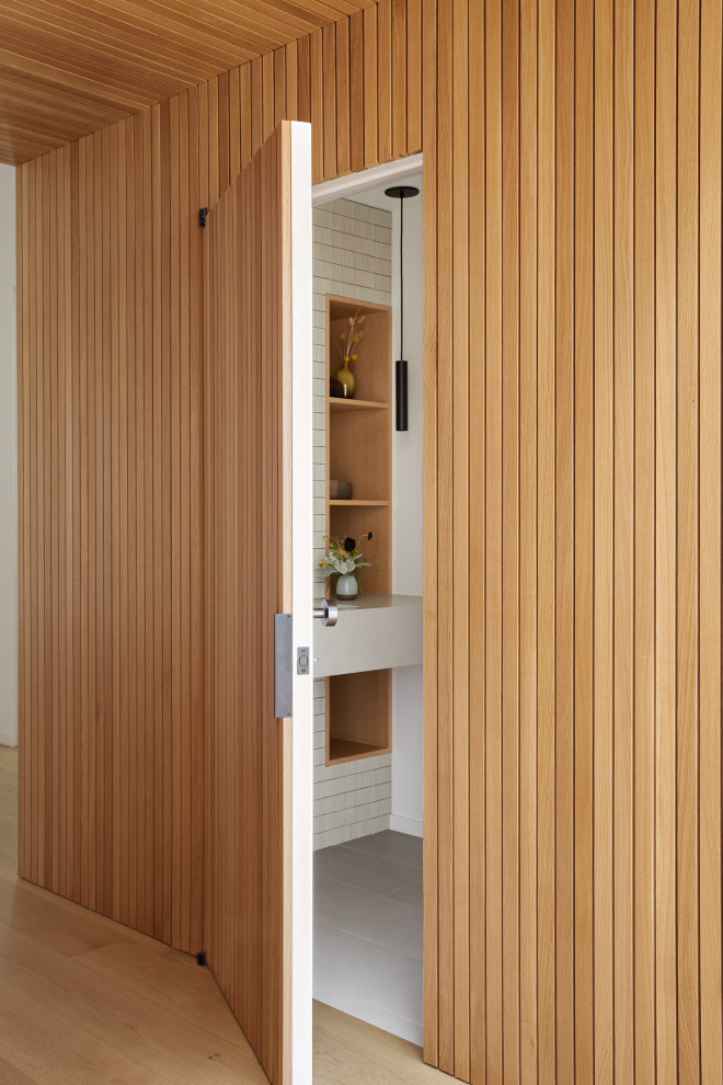 Foto de distribuidor abovedado moderno de tamaño medio con paredes blancas, suelo de madera clara, puerta pivotante, puerta de madera clara, suelo marrón y madera