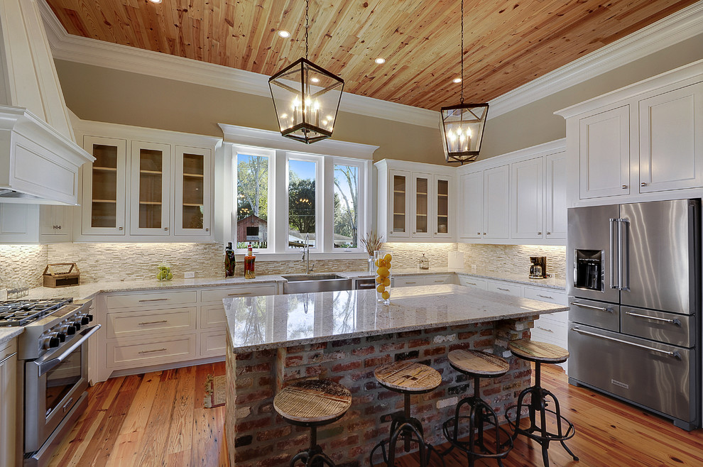 Design ideas for a transitional u-shaped kitchen in New Orleans with a farmhouse sink, recessed-panel cabinets, white cabinets, beige splashback, stainless steel appliances, medium hardwood floors and with island.