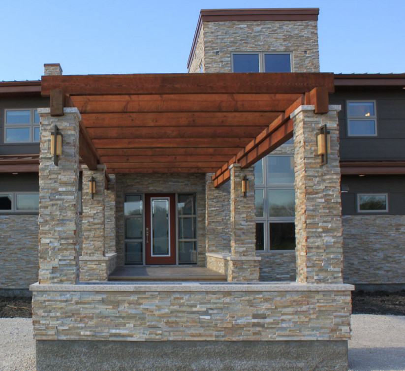 Photo of a large contemporary two-storey grey exterior in Orange County with stone veneer and a flat roof.