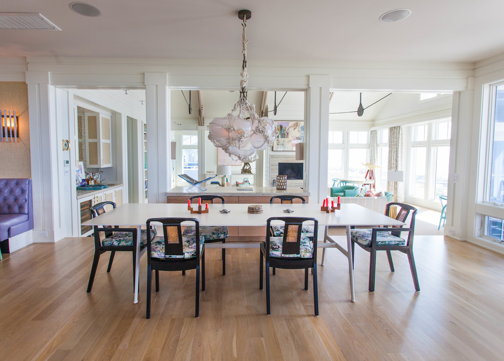 This is an example of a large beach style dining room in Wilmington with white walls, no fireplace, light hardwood floors and brown floor.