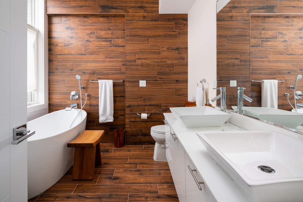 Example of a large trendy master brown tile and wood-look tile porcelain tile, brown floor and single-sink freestanding bathtub design in New York with flat-panel cabinets, white cabinets, a one-piece toilet, brown walls, quartz countertops, white countertops, a floating vanity and a vessel sink