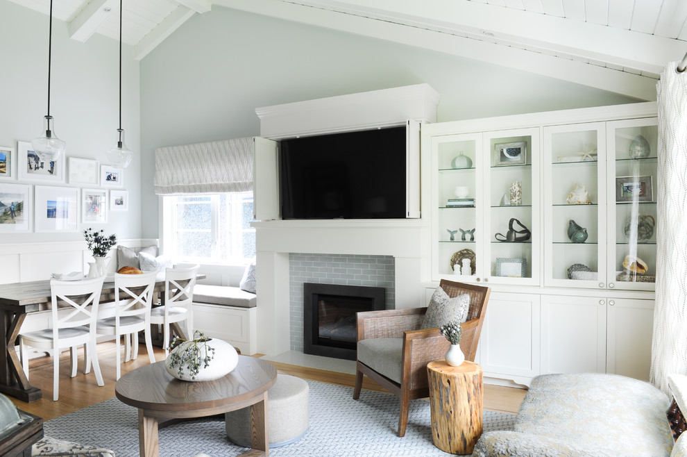 Inspiration for a small beach style open concept family room in Vancouver with grey walls, light hardwood floors, a standard fireplace, a tile fireplace surround, a concealed tv and brown floor.
