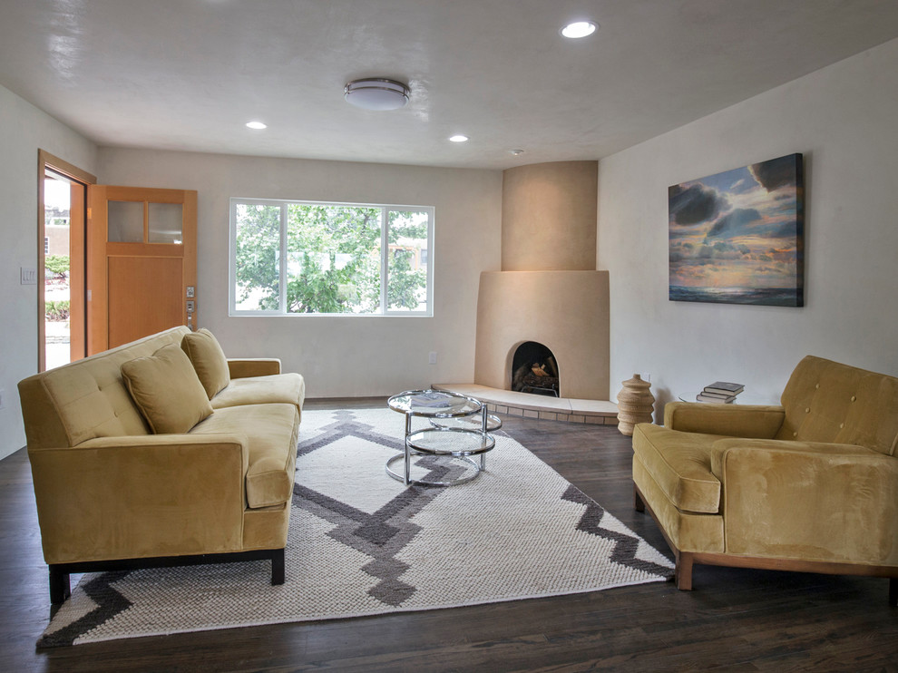 Photo of a mid-sized contemporary open concept living room in Albuquerque with white walls, dark hardwood floors, a corner fireplace and a plaster fireplace surround.