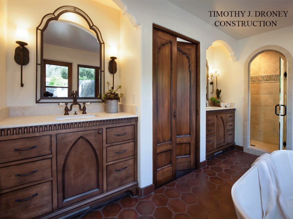 Design ideas for a small mediterranean master bathroom in Los Angeles with furniture-like cabinets, distressed cabinets, a freestanding tub, a corner shower, white tile, ceramic tile, white walls, terra-cotta floors, an undermount sink, limestone benchtops, brown floor and a hinged shower door.