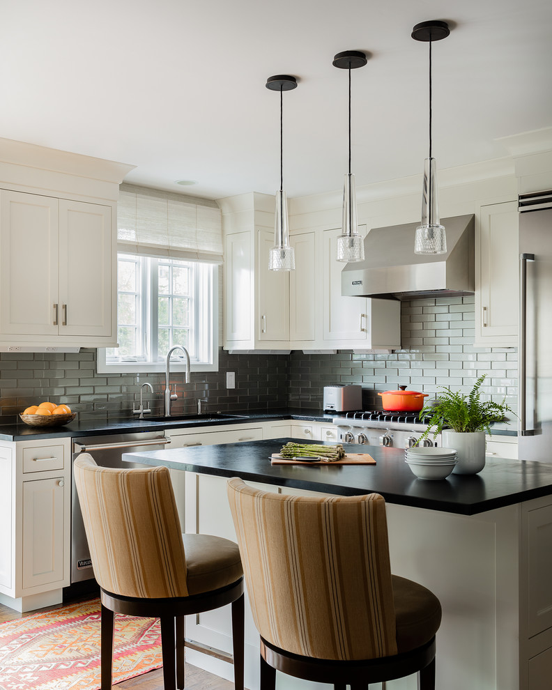 Example of a large transitional l-shaped light wood floor and brown floor eat-in kitchen design in Boston with flat-panel cabinets, white cabinets, gray backsplash and an island