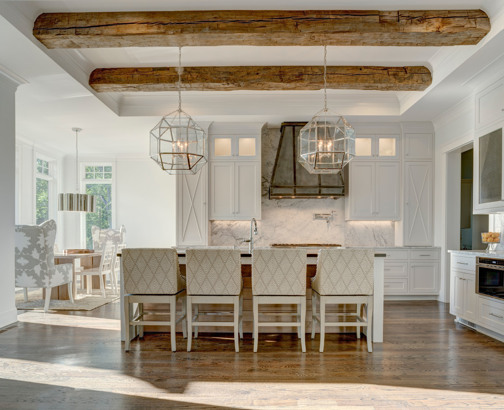 This is an example of an expansive country l-shaped eat-in kitchen in Charlotte with shaker cabinets, white cabinets, white splashback, medium hardwood floors, with island, stone slab splashback, brown floor, an undermount sink, stainless steel appliances, marble benchtops and grey benchtop.