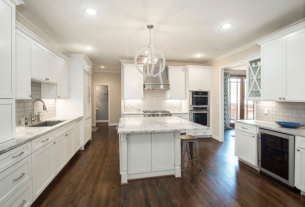 Inspiration for a large transitional u-shaped medium tone wood floor open concept kitchen remodel in Dallas with an undermount sink, shaker cabinets, white cabinets, quartz countertops, white backsplash, porcelain backsplash, stainless steel appliances and an island
