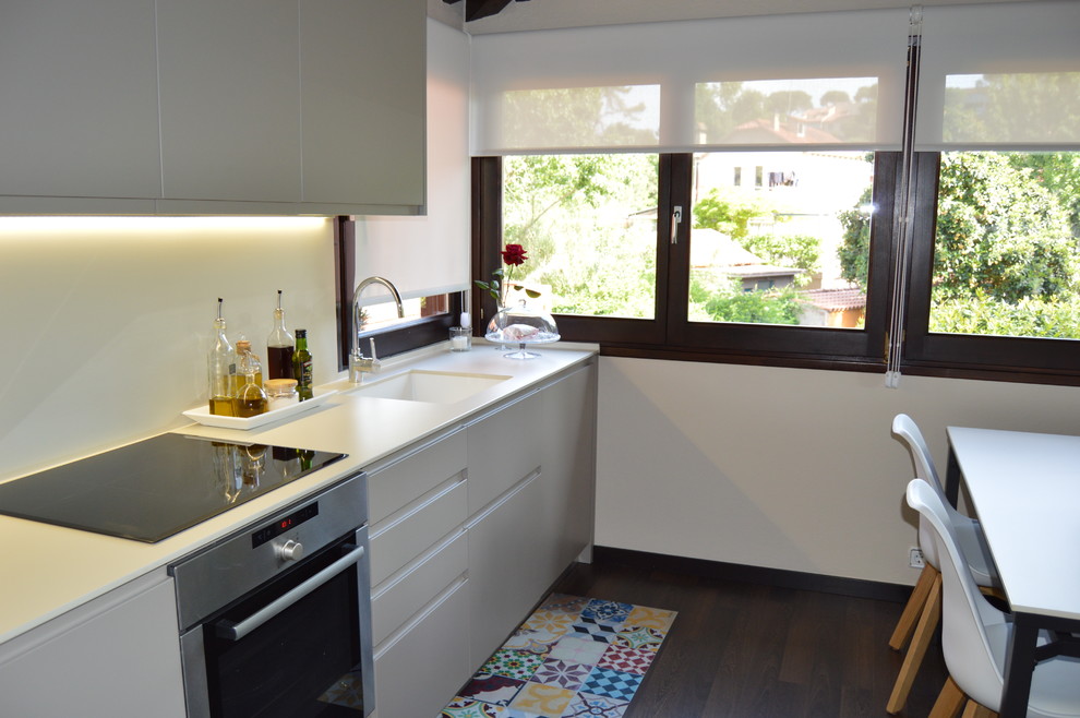 This is an example of a large country single-wall eat-in kitchen in Barcelona with an undermount sink, flat-panel cabinets, grey cabinets, beige splashback, stainless steel appliances, no island, brown floor and dark hardwood floors.