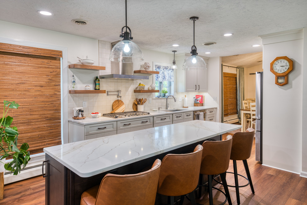 Inspiration for a mid-sized transitional laminate floor and brown floor kitchen remodel with shaker cabinets, beige cabinets, quartz countertops, white backsplash, ceramic backsplash, stainless steel appliances and white countertops