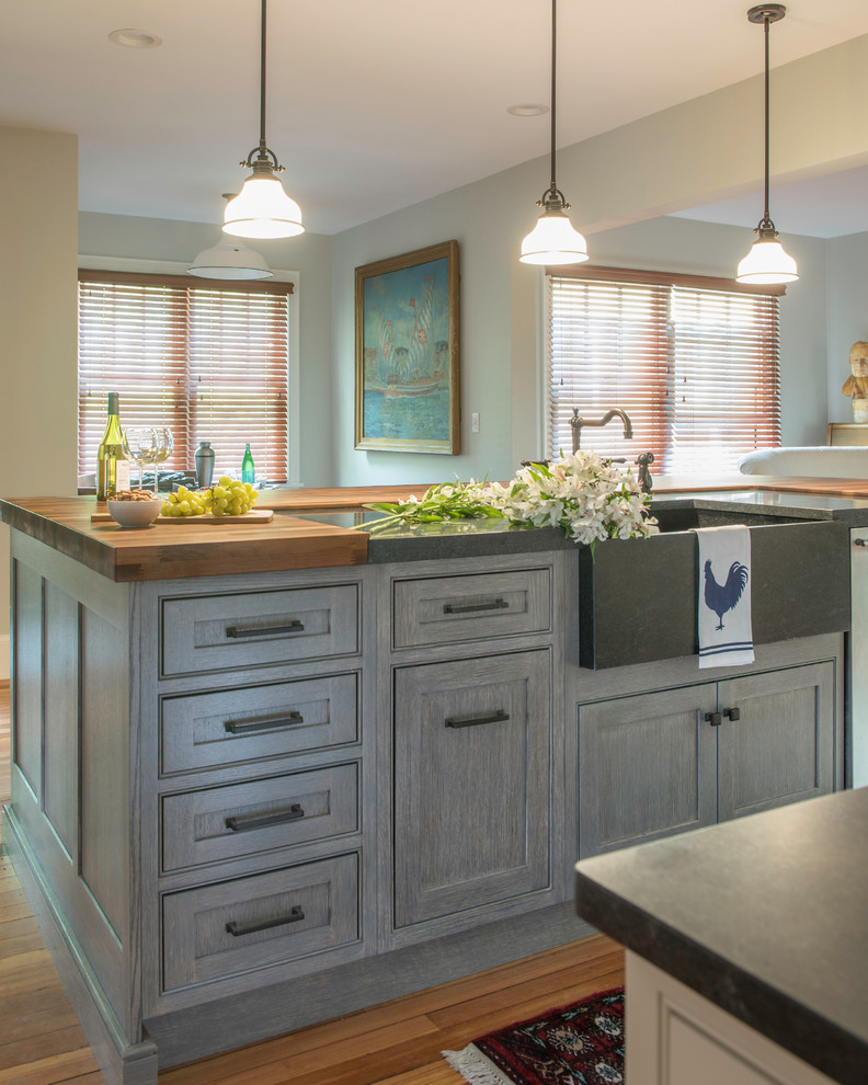 Inspiration for a mid-sized country galley open plan kitchen in Boston with a farmhouse sink, beaded inset cabinets, white cabinets, wood benchtops, blue splashback, cement tile splashback, panelled appliances, medium hardwood floors, with island, brown floor and black benchtop.