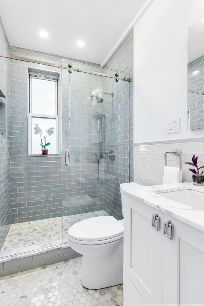 Example of a large trendy master beige tile and ceramic tile mosaic tile floor, beige floor and single-sink sliding shower door design in New York with shaker cabinets, white cabinets, a two-piece toilet, white walls, a drop-in sink, marble countertops, beige countertops, a niche and a built-in vanity