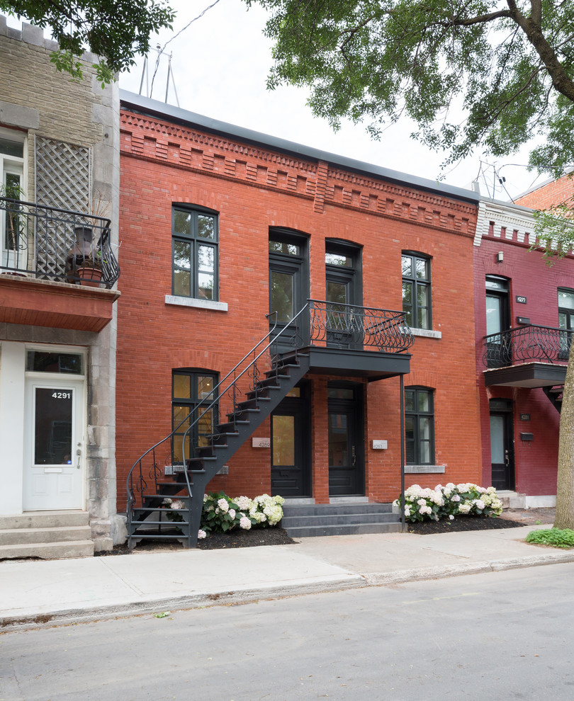 Photo of a small contemporary two-storey brick red duplex exterior in Montreal with a flat roof.