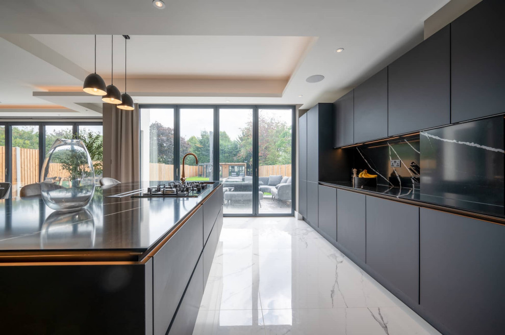 Inspiration for a large modern l-shaped open plan kitchen in Hertfordshire with flat-panel cabinets, black splashback, black appliances, marble flooring, an island, black worktops and a drop ceiling.
