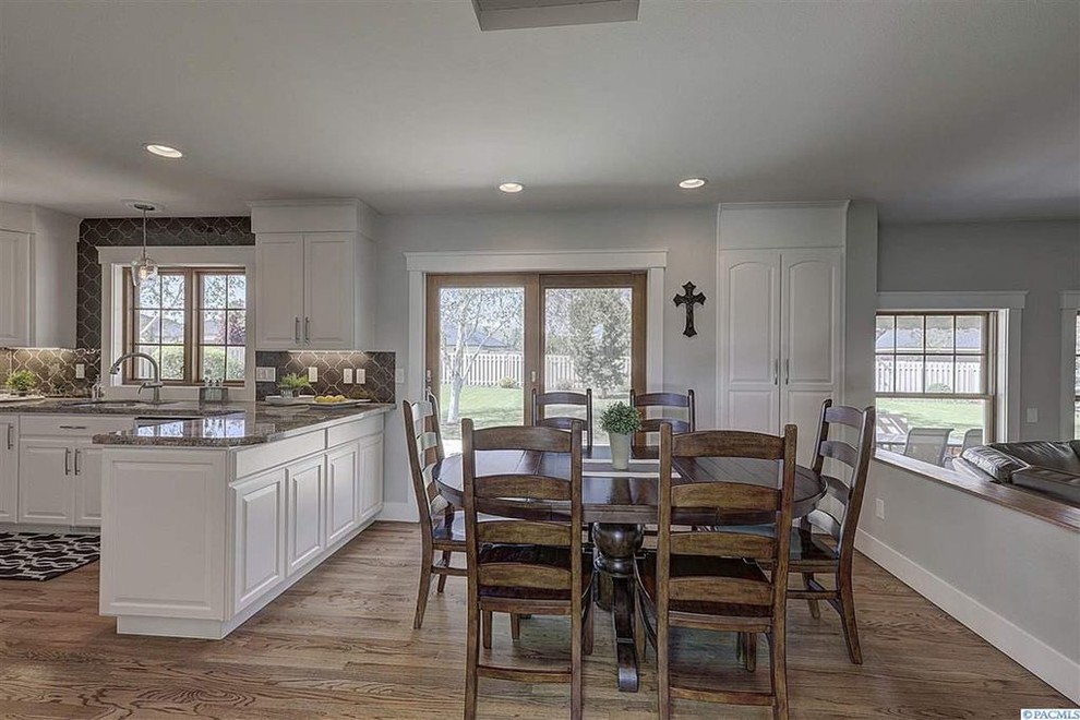 Inspiration for a transitional u-shaped medium tone wood floor and brown floor eat-in kitchen remodel in Seattle with an undermount sink, raised-panel cabinets, white cabinets, granite countertops, brown backsplash, porcelain backsplash, stainless steel appliances and brown countertops