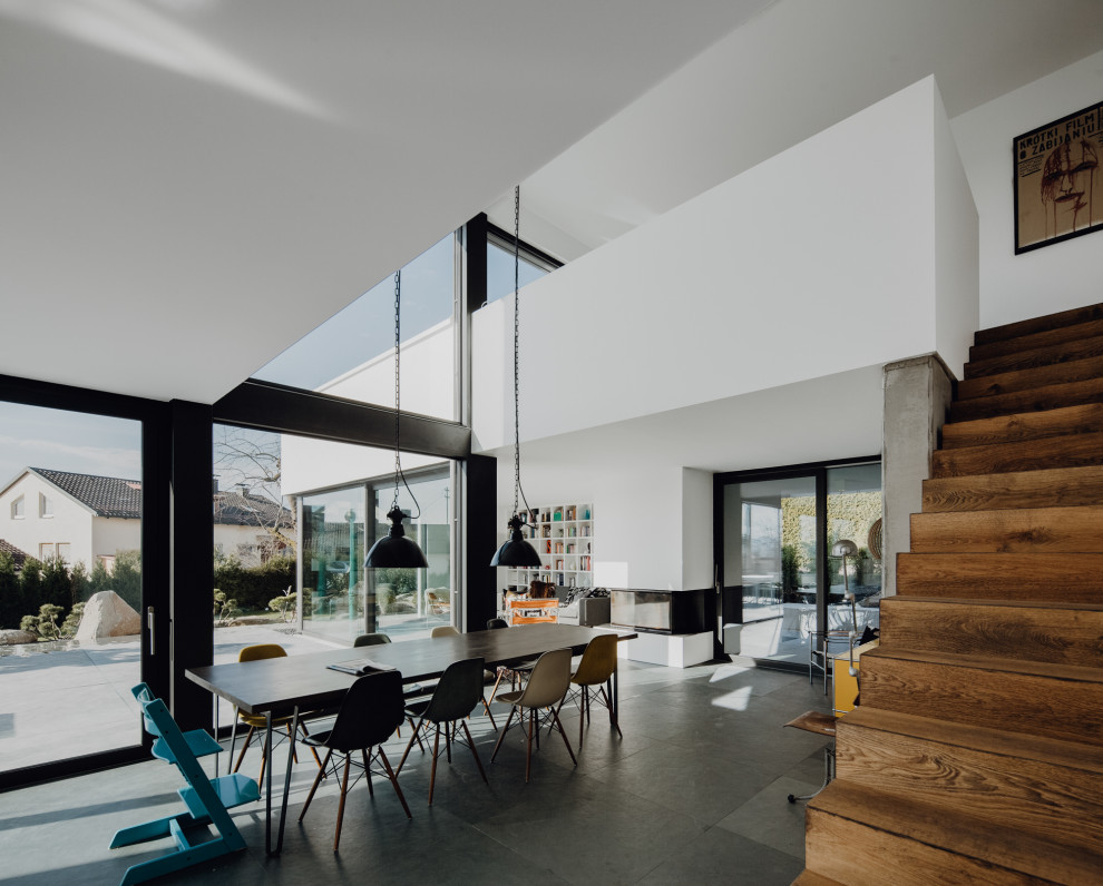 Design ideas for a large modern open plan dining in Munich with white walls, slate floors, a wood stove, a plaster fireplace surround and black floor.