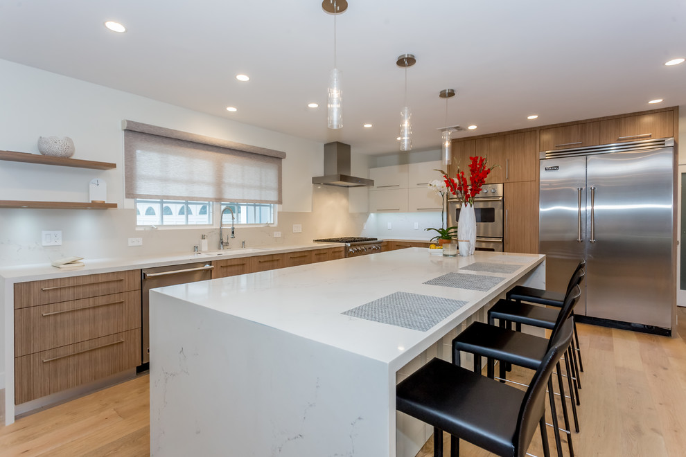Large trendy l-shaped light wood floor and beige floor open concept kitchen photo in San Francisco with an undermount sink, flat-panel cabinets, medium tone wood cabinets, marble countertops, stainless steel appliances and an island