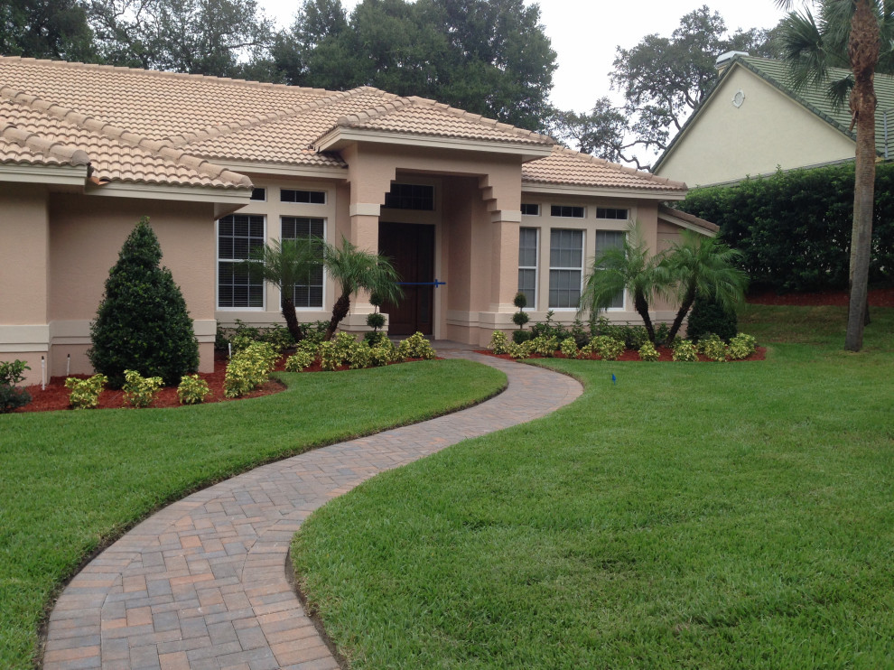 Photo of a mid-sized tropical front yard full sun xeriscape for spring in Orlando with with path and concrete pavers.