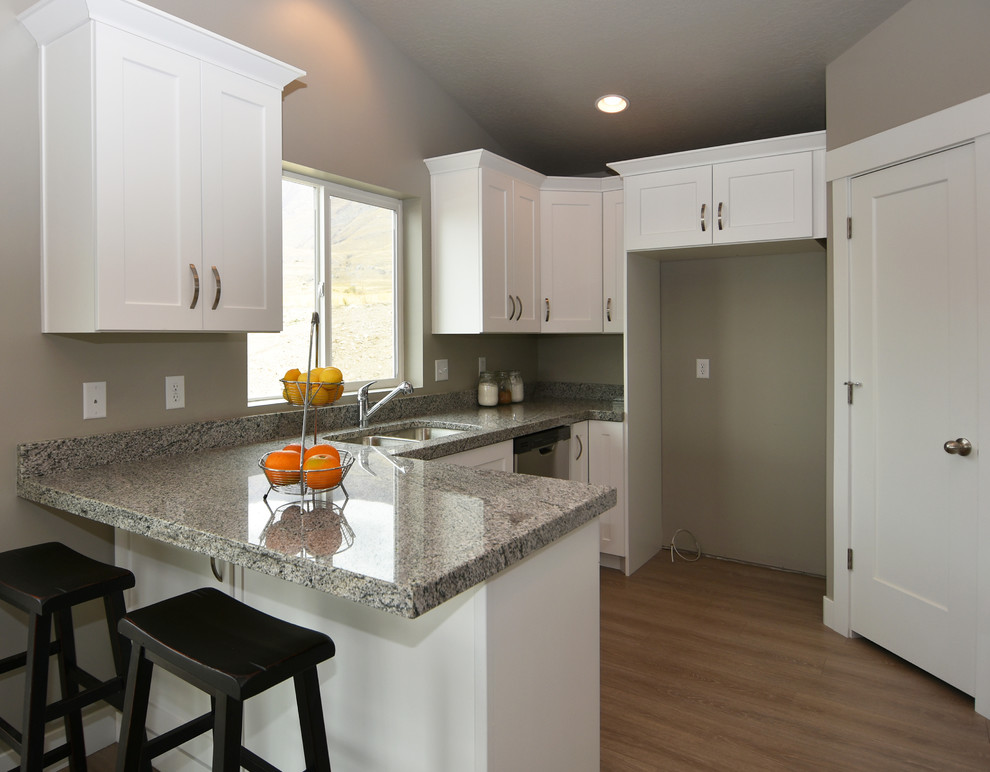 Mid-sized arts and crafts u-shaped eat-in kitchen in Salt Lake City with a double-bowl sink, shaker cabinets, white cabinets, granite benchtops, stainless steel appliances, laminate floors and a peninsula.