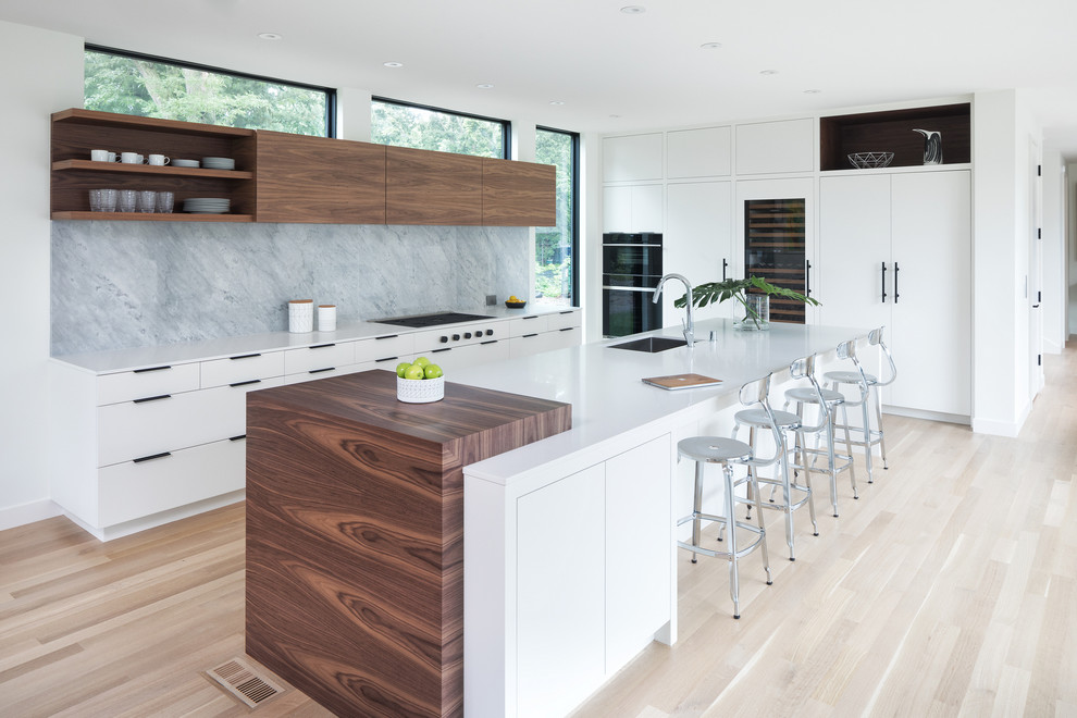 Contemporary kitchen in Minneapolis with an undermount sink, flat-panel cabinets, white cabinets, quartz benchtops, grey splashback, marble splashback, panelled appliances, light hardwood floors, with island, white benchtop and beige floor.