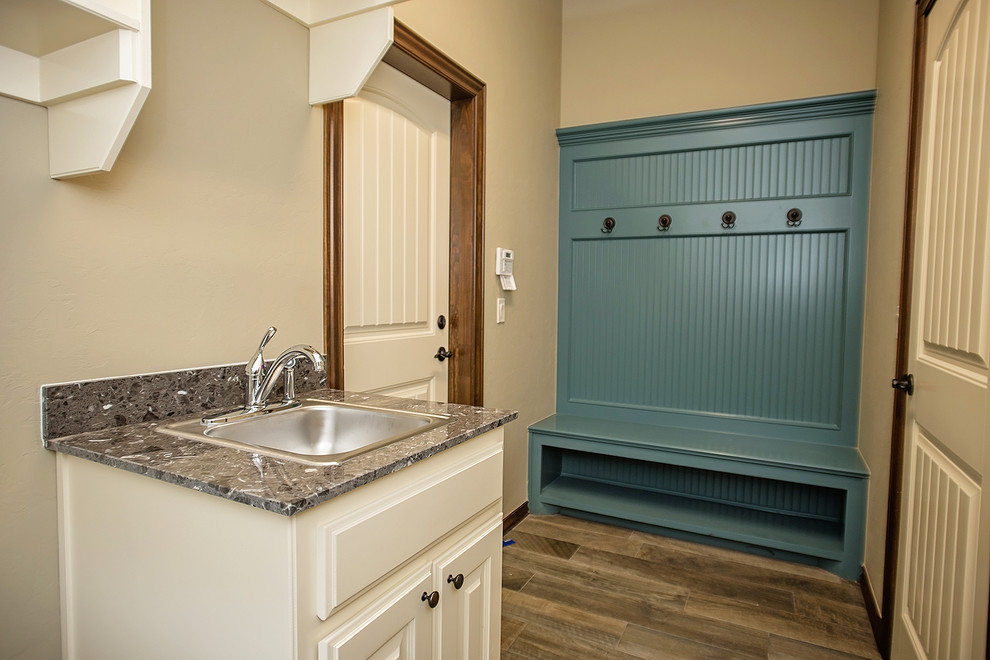Mid-sized transitional galley laundry room in Oklahoma City with a single-bowl sink, raised-panel cabinets, white cabinets, marble benchtops, medium hardwood floors and brown floor.