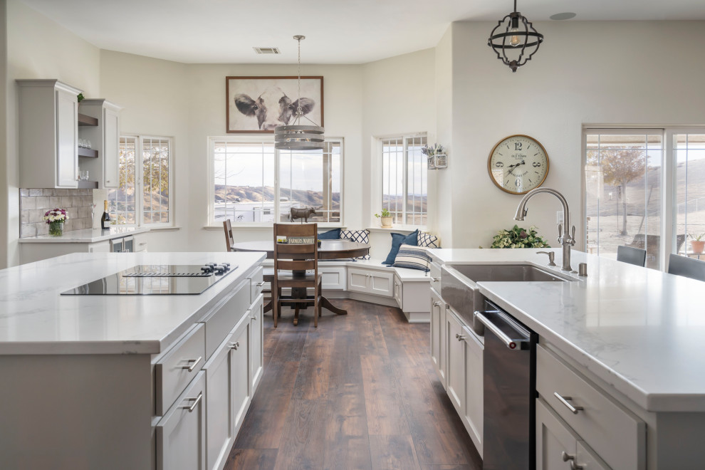 Inspiration for a huge transitional single-wall vinyl floor and brown floor open concept kitchen remodel in Los Angeles with a farmhouse sink, shaker cabinets, gray cabinets, quartz countertops, gray backsplash, ceramic backsplash, stainless steel appliances, two islands and white countertops