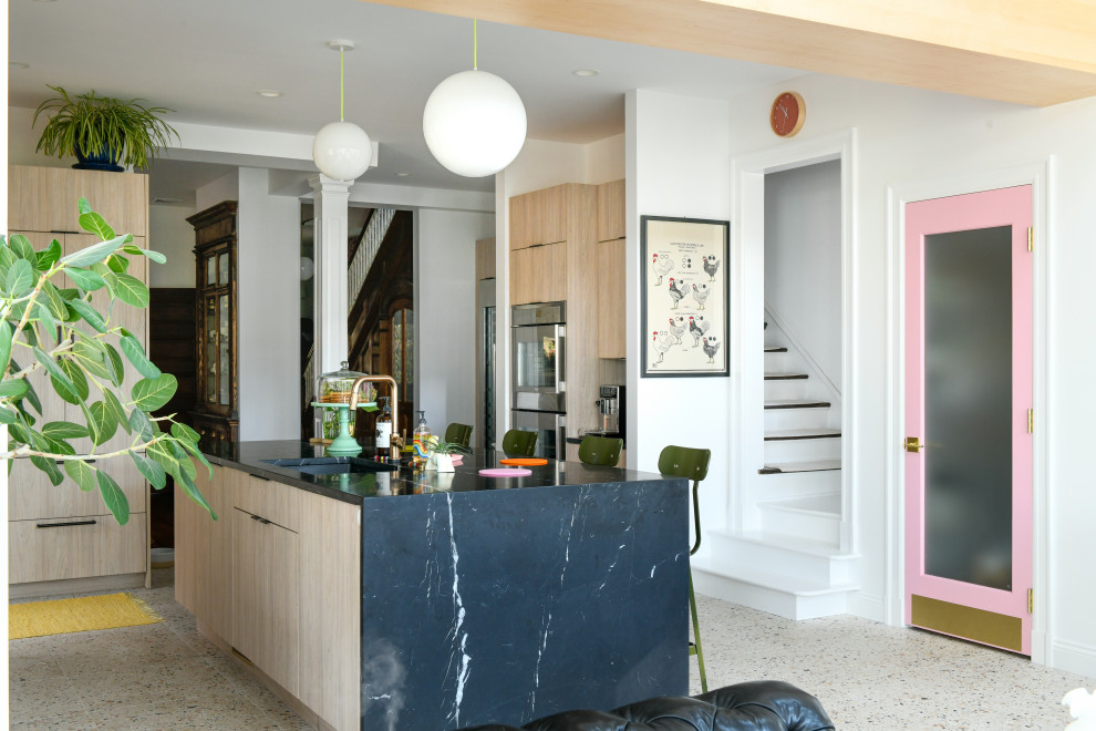Réalisation d'une cuisine ouverte vintage en bois clair avec un placard à porte plane, plan de travail en marbre, une crédence noire, une crédence en marbre, un électroménager en acier inoxydable, un sol en terrazzo et îlot.