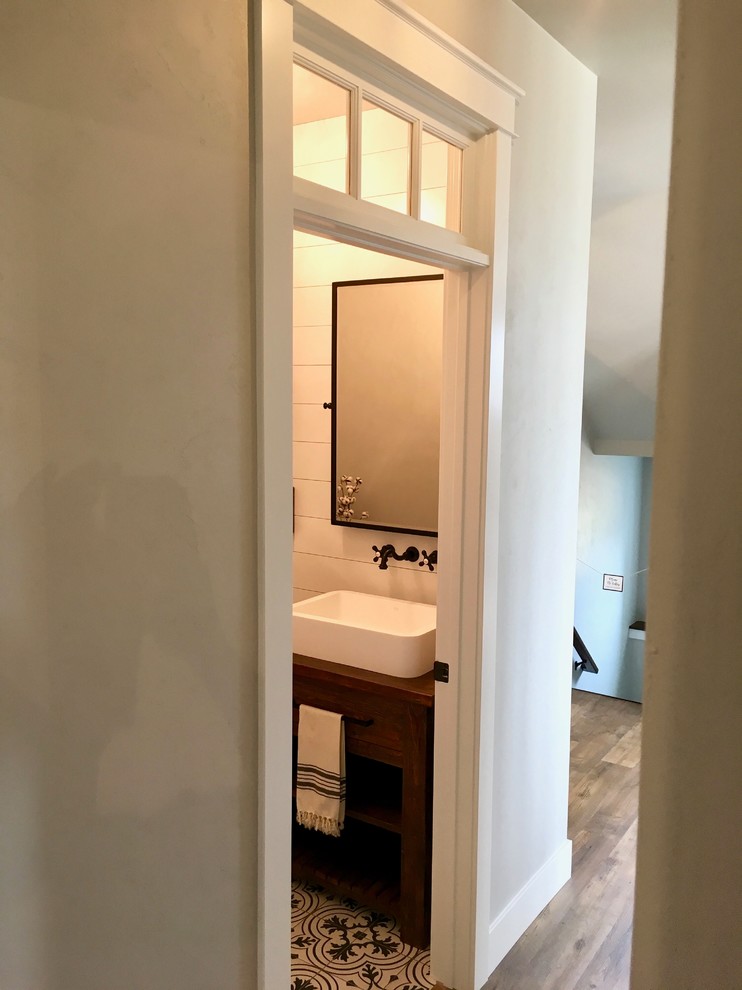 Photo of a small country 3/4 bathroom in Other with open cabinets, dark wood cabinets, a one-piece toilet, grey walls, mosaic tile floors, a trough sink, wood benchtops and black floor.