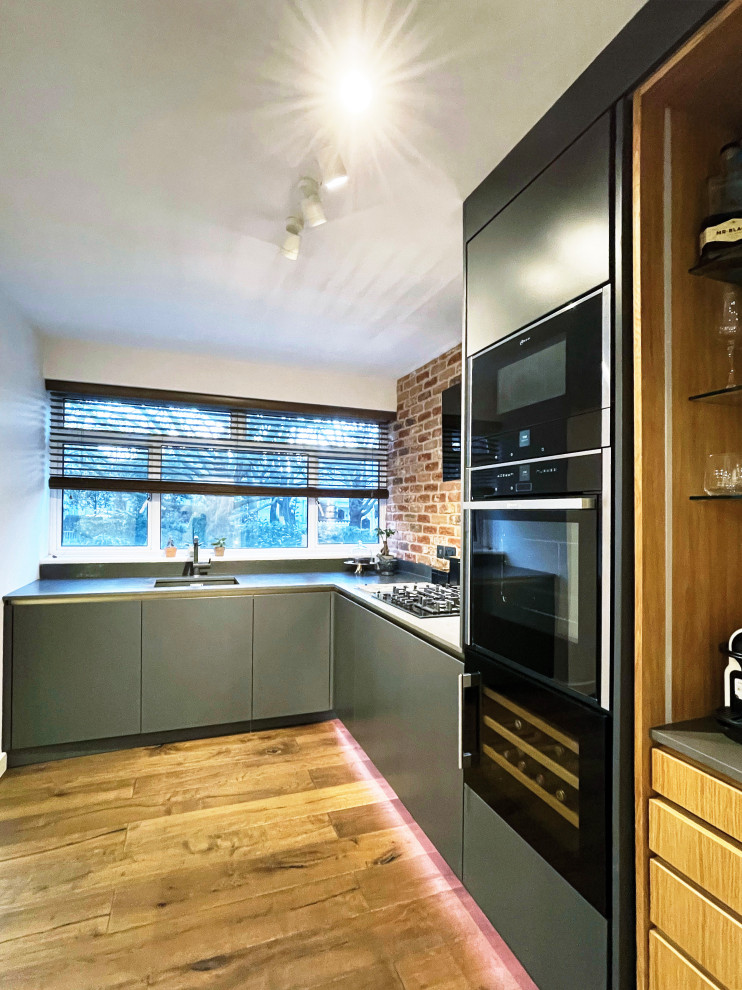 Mid-sized modern l-shaped kitchen pantry in New York with a drop-in sink, light hardwood floors, no island, brown floor, brown splashback and brick splashback.