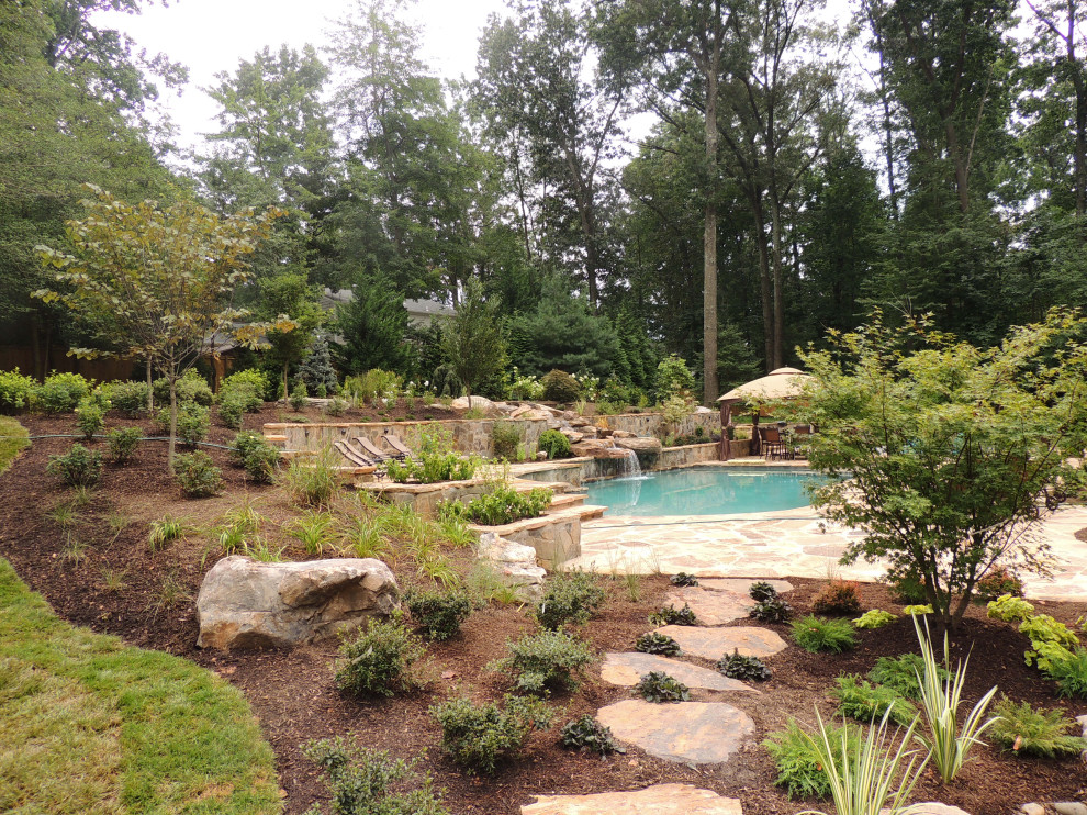 Inspiration for a large country backyard custom-shaped pool in DC Metro with natural stone pavers.