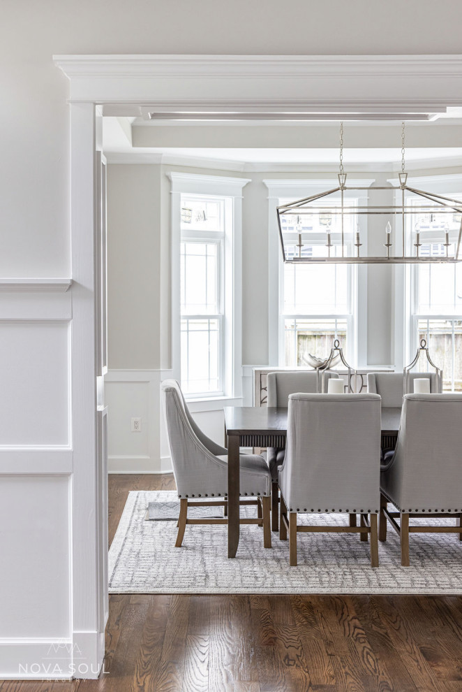 This is an example of a large classic enclosed dining room in DC Metro with grey walls, medium hardwood flooring, brown floors, a coffered ceiling and wainscoting.