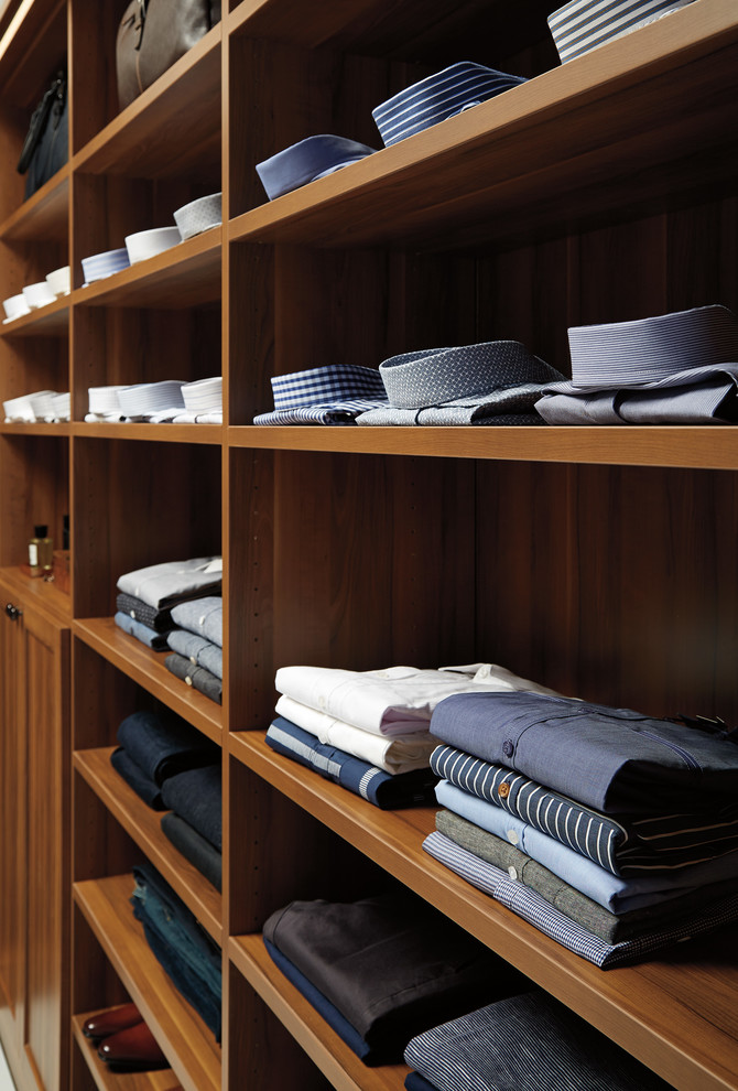 Traditional men's walk-in wardrobe in Other with shaker cabinets, medium wood cabinets and concrete floors.