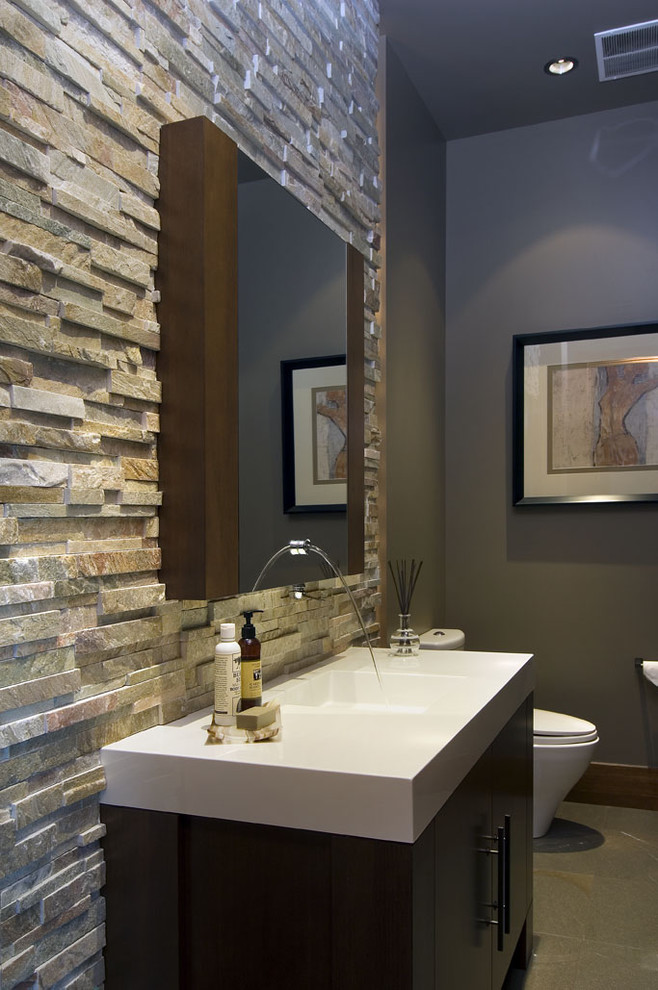 Photo of a contemporary powder room in Vancouver with stone tile and an integrated sink.