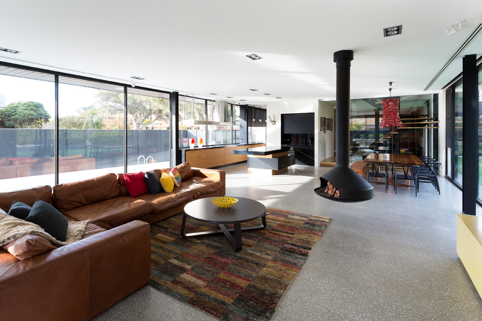 This is an example of a large contemporary open concept living room in Melbourne with a hanging fireplace, white walls and concrete floors.