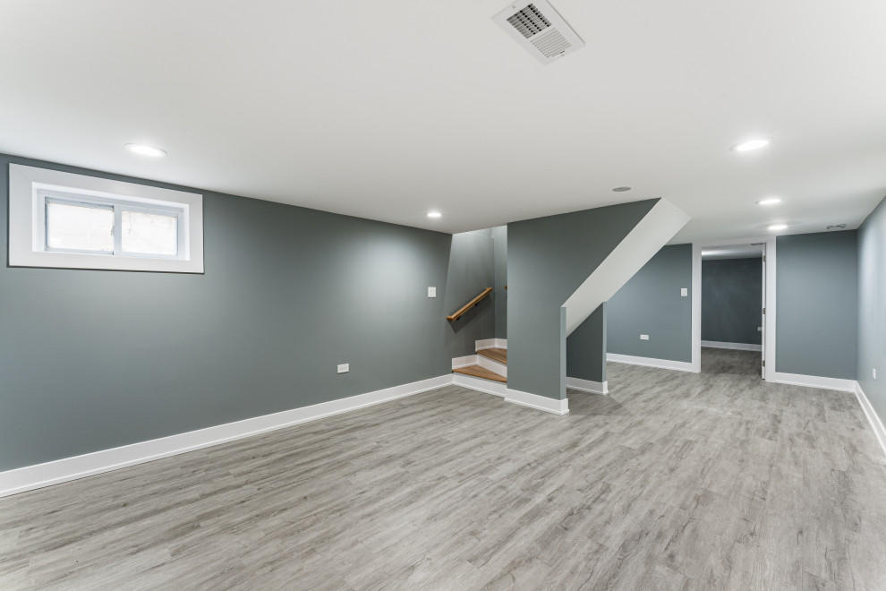 Réalisation d'un sous-sol minimaliste donnant sur l'extérieur et de taille moyenne avec un mur gris, un sol en vinyl et un sol gris.