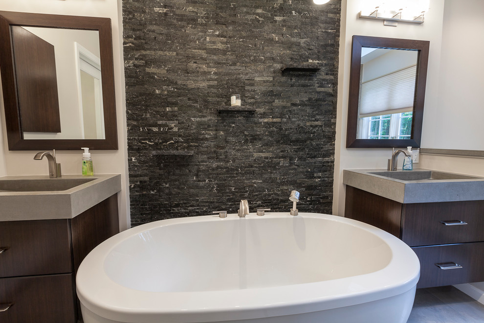 Large contemporary master bathroom in New York with flat-panel cabinets, dark wood cabinets, a freestanding tub, an alcove shower, a two-piece toilet, multi-coloured tile, matchstick tile, grey walls, porcelain floors, an integrated sink, concrete benchtops, grey floor and a hinged shower door.
