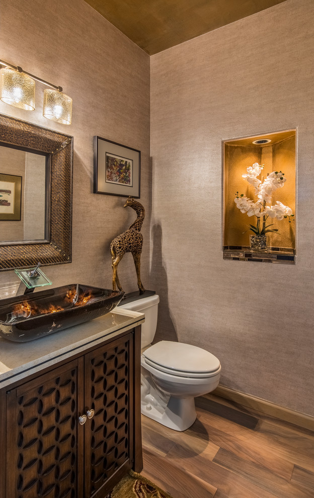 This is an example of a small transitional powder room in Other with furniture-like cabinets, medium wood cabinets, a one-piece toilet, brown tile, mosaic tile, medium hardwood floors, a vessel sink, travertine benchtops and brown floor.