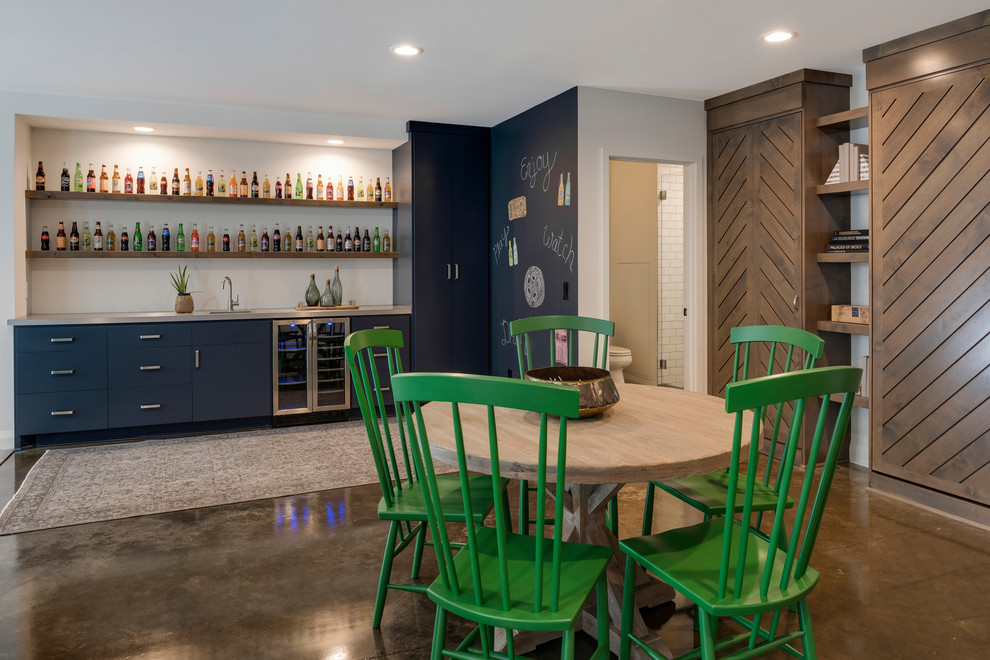 This is an example of a transitional single-wall wet bar in Minneapolis with a drop-in sink, flat-panel cabinets, blue cabinets, brown floor, grey benchtop and concrete floors.
