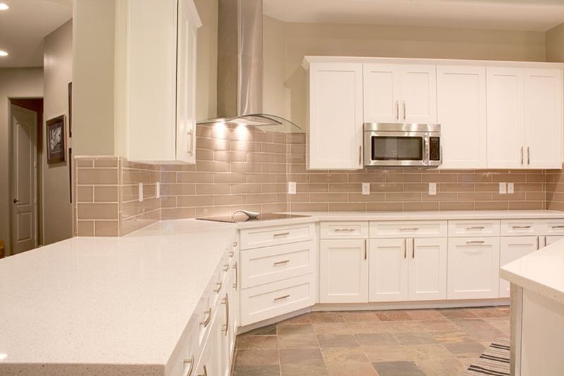Large transitional l-shaped slate floor kitchen photo in Phoenix with shaker cabinets, white cabinets, quartz countertops, beige backsplash, subway tile backsplash and an island
